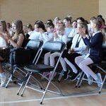 Ubrani na galowo uczniowie siedzą na krzesełkach i biją brawo.JPG