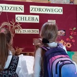 Dwie uczennice przed gazetką z napisem Tydzień zdrowego chleba z datą projektu..jpeg