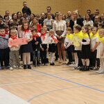 Dzieci ubrane na galowo w czerwobych i żółtych chustach _ za nimi stoją rodzice.jpg