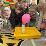 Na zdjęciu widoczne są dzieci z grupy „Pszczółki” zgromadzone wokół przygotowanego doświadczenia z balonem..jpg