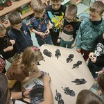Przedszkolaki z grupy Sówki odbijają ślady dinozaura na szarym papierze..jpg