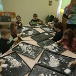 Przedszkolaki z grupy Sówki rozbijają masę gipsowa na czarnych podkładkach..jpg