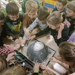Przedszkolaki z grupy Sówki układają figurki dinozaurów na makiecie wulkanu..jpg