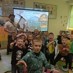 Zdjęcie grupowe przedszkolaków z grupy Sówki z dinozaurami. W tle znajduje się projekcja o dinozaurach..jpg