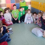 Dzieci siedzą w kręgu_ kobieta na fantomie pokazuje_ jak sprawdzić czy osoba nieprzytomna oddycha.jpg