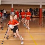 Na pierwszym planie widoczny zawodnik biegnący z piłką do rugby.jpg
