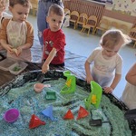 Dzieci z grupy Żabki bawią się w piaskownicy kolorowym ryżem..jpg