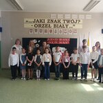 Uczestnicy konkursu wraz z nauczycielami stoją przed dekoracją..jpg
