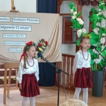 Dwie dziewczynki w białych bluzkach i czerwonych_ z wiankami na głowach_  spódniczkach podczas występu.jpg