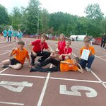Chłopaki z medalami pozują na bieżni stadionu.jpg