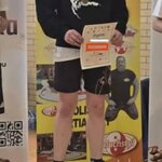 Chłopiec z medalem trzymający dyplom na podium na I miejscu