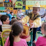Chłopiec w przebraniu pszczelarza prezentuje dzieciom plaster miodu..jpg