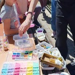 Na stole stoją pudełka z koralikami.jpg