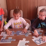 Trzech chłopców układa z puzzli wielki banknot.jpg