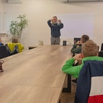 Prowadzący zajęcia mężczyzna demonstruje słoiki w których znajduje się woda na róznych etapach procesu oczyszczania.jpg