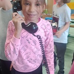 Dziewczynka trzyma przy uchu słuchawkę telefoniczną.jpg