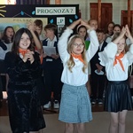 Grupa dziewczynek z pomarańczowymi chusteczkami na szyjach trzyma w górze ręce.jpg