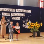 Uroczyste Rozpoczęcie Roku Szklonego_ na scenie stoi nauczyciel_ trzyma w rękach notatnik .jpg