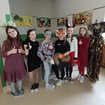 Grupa przebranych dziewcząt stoi w stołówce_ w tle widoczne duże zdjęcia z owocami i warzywami.jpg