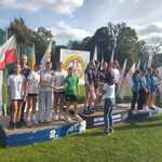 Dekoracja zwycięzców_ nasza reprezentacja dziewcząt z trenerem stoi na podium na drugim miejscu.jpg