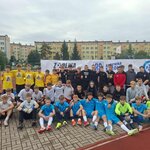 5 drużyn piłkarskich w białych, niebieskich, czarnych i żółtych strojach podczas Turnieju w ramach programu Aktywna Szkoła  stojących przed banerem Fundacji Orły Sportu