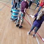 Uczeń trzyma za ręce dzieci stojące obok. Kuca próbując przekazać koledze obok hula hop..j.jpg