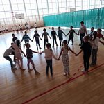 Dzieci stoją w kręgu trzymając się za ręce. Podają sobie hula hop nie mogąc puścić rąk..jp.jpg