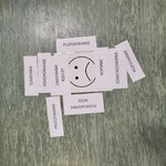 Na zdjęciu widzimy kartkę z narysowaną smutną buźką, wokół której rozmieszczono małe kartoniki z różnymi napisami np. plotkowanie, kopanie, zabieranie rzeczy.