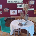 W tle tablica z napisem Tydzień zdrowego chleba_ z przodu stolik nakryty białym obrusem_ na nim koszyczek z chlebem.jpg