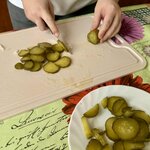 Na zdjęciu widać osobę krojącą ogórki oraz ogórki znajdujące się na talerzu.