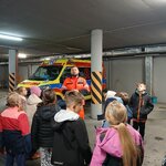 Uczniowie stają w garażu_ słuchają poleceń ratownika_ za ratownikiem stoi karatka..jpg