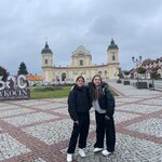 uczennice klasy 5a (Milana Kryzhanivska i Amelia Kruszyńska) stojące na tle centrum Tykocina (Urzędu Miejskiego i pomnika z okazji 600 rocznicy założenia miasta)