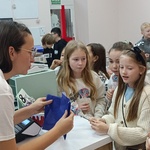 Troje dzieci stoi przed ekspedientką_ dziewczynka płaci za towar.jpg