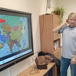 Na ekranie widać mapę_ z przodu stoi mężczyzna_ w głębi widać kobietę.jpg