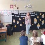 Na środku stoi prowadząca_ w tle dekoracja z nazwą konkursu.jpg