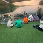 Uczniowie uczestniczą w zajęciach edukacyjnych w Muzeum Przyrodniczym_ siedząc przed wysta.jpg