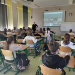 Nauczycielka stojąca przy biurku opowiadająca dzieciom o koncentracji i pokazująca padleta ze szkoły w Islandii.