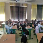 Uczniowie siedzący w ławkach wykonujący ćwiczenie na palcach