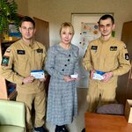 Dyrektor szkoły oraz dwóch strażaków stojących w gabinecie i trzymających czujniki dymu oraz czujniki tlenku węgla.
