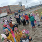 Grupa Sówek i Żabek podczas spaceru z okazji pierwszego Dnia Wiosny rozdaje kwiaty wykonane z papieru przechodniom..jpg