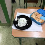 Na małym stoliku stoi czarny talerz z porcją białej pasty i pojemnik z kromkami pieczywa. .jpg