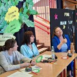 Stół jury z dokumentami_ mikrofonem i rekwizytami za nim dekoracyjne drzewo z napisami ora.jpg