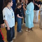 Wręczanie medalu uczestnikowi osoby dorosłe zakładają medal na szyję_ obok stoją inni nagr.jpg