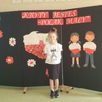 Dziewczynka w strju galowym_ w tle tablica z nazwą konkursu.jpg