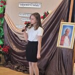 Dziewczynka w okularach_ białej koszuli i czarnej spódnicy śpiewa do mikrofonu na tle deko.jpg