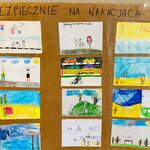 Tablica z hasłem „Bezpiecznie na wakacjach 3B”, na której przypięto dziecięce rysunki przedstawiające zasady bezpiecznego wypoczynku, m.in. nad wodą i na rowerze.
