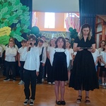 Trzy osoby ustawione w jednej linii. Po lewej stronie znajduje się dziecko trzymające mikrofon blisko ust.jpg