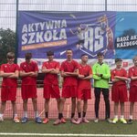 Drużyna szkolna w czerwonych strojach pozuje na boisku podczas wydarzenia sportowego.jpeg