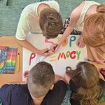 Uczniowie wspólnie tworzą plakat promujący wzajemny szacunek, wsparcie i przeciwdziałanie przemocy rówieśniczej
