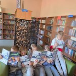 Klasa 2c czyta lekturę „Psie troski” Toma Justyniarskiego w bibliotece. Uczniowie siedzą na kanapie i samodzielnie poznają losy bohaterów książki.
